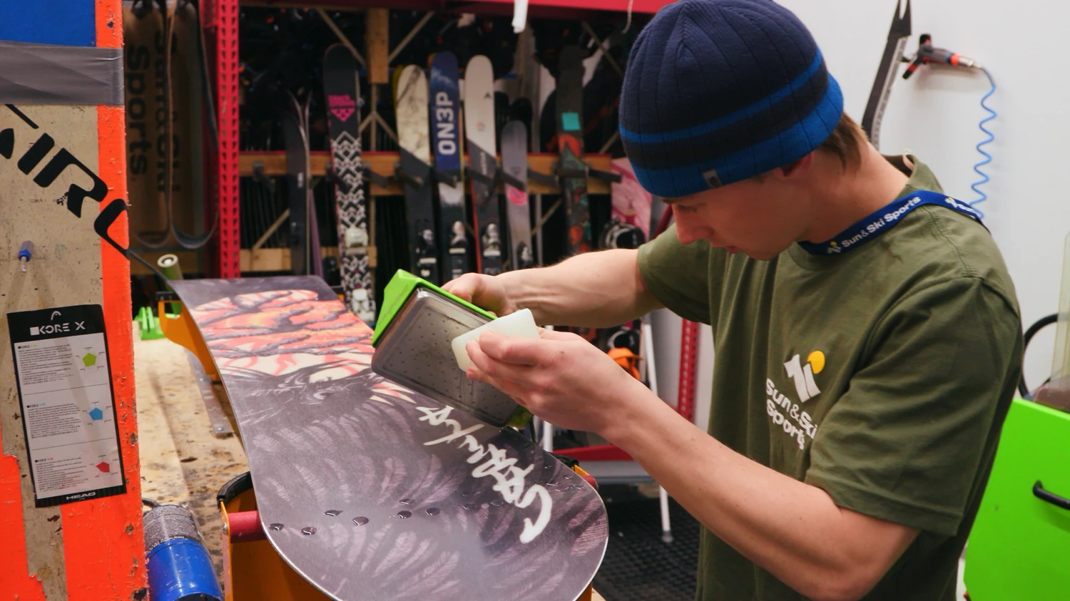 An Outdoor Expert performing snowboard shop services on a snowboard at Sun & Ski Sports